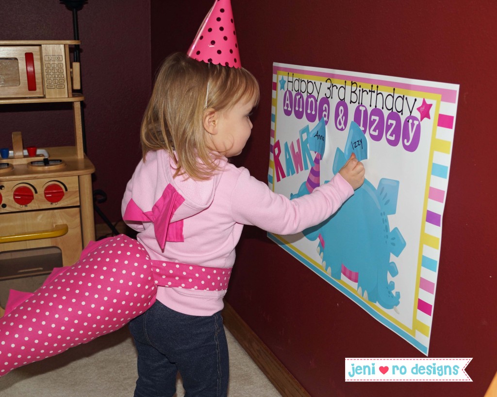 girl in dinosaur tail playing pin the scale on the dino printable game